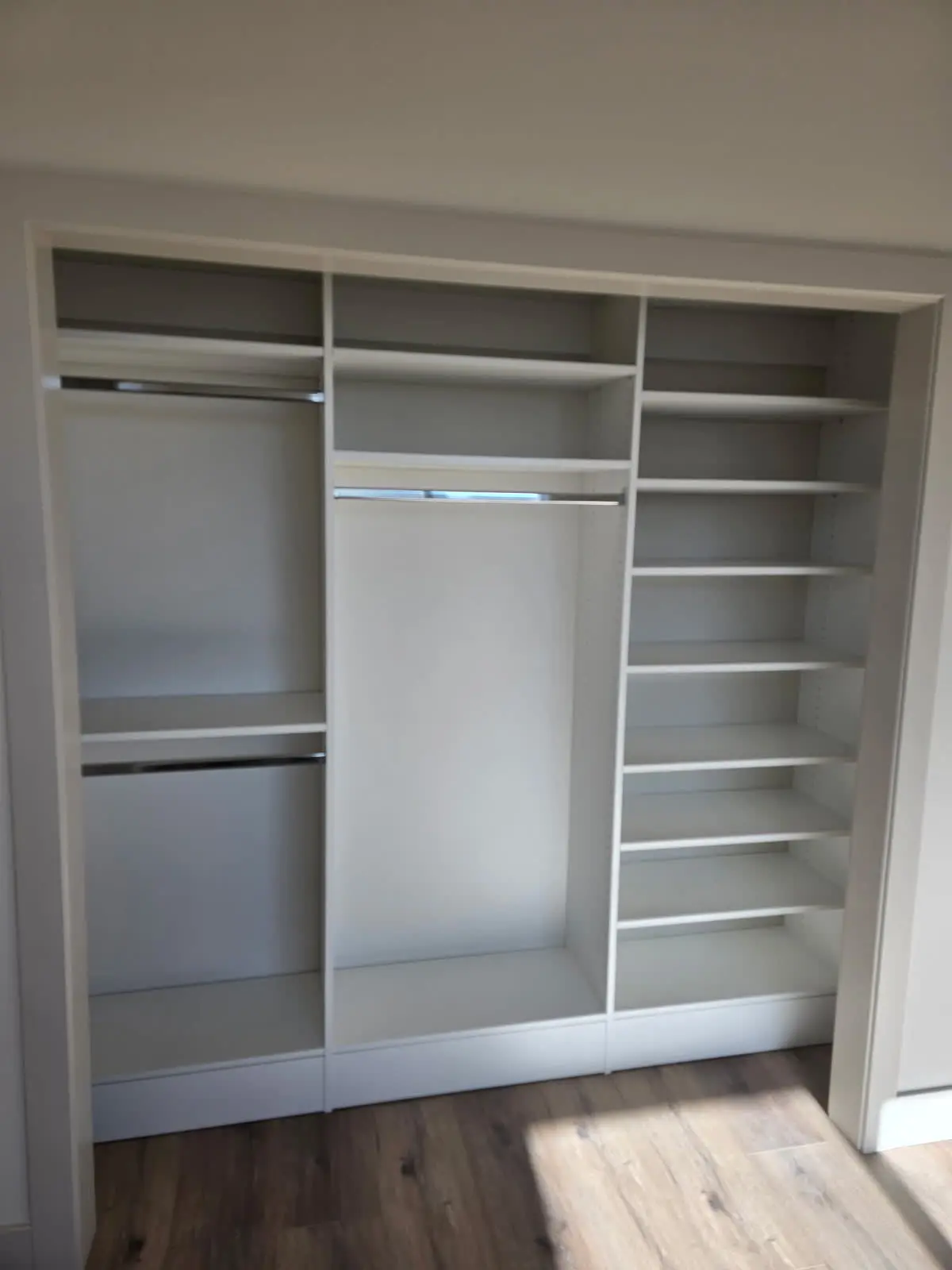 White reach-in closet system with hanging and shelves by DC Cabinets