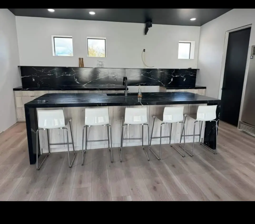 Modern kitchen island with black marble waterfall counter and bar stools by DC Cabinets