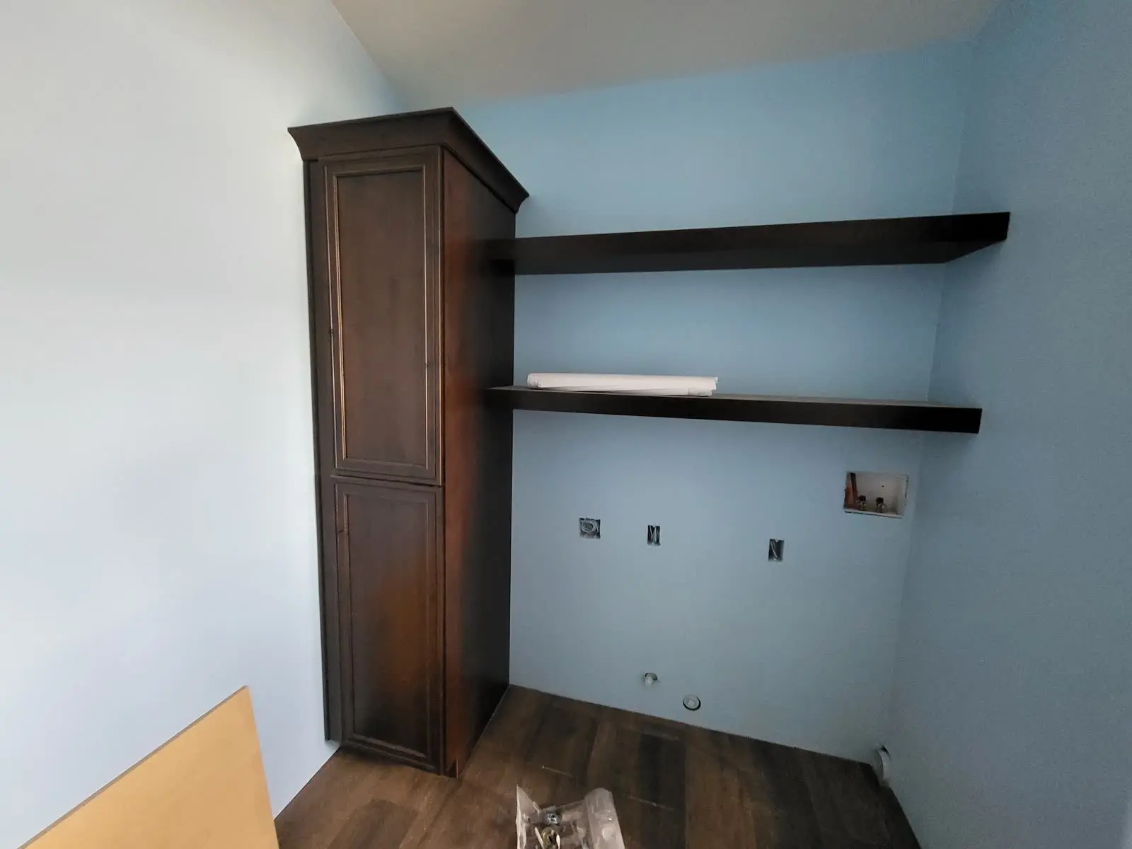 Tall stained laundry room cabinet with floating shelves by DC Cabinets
