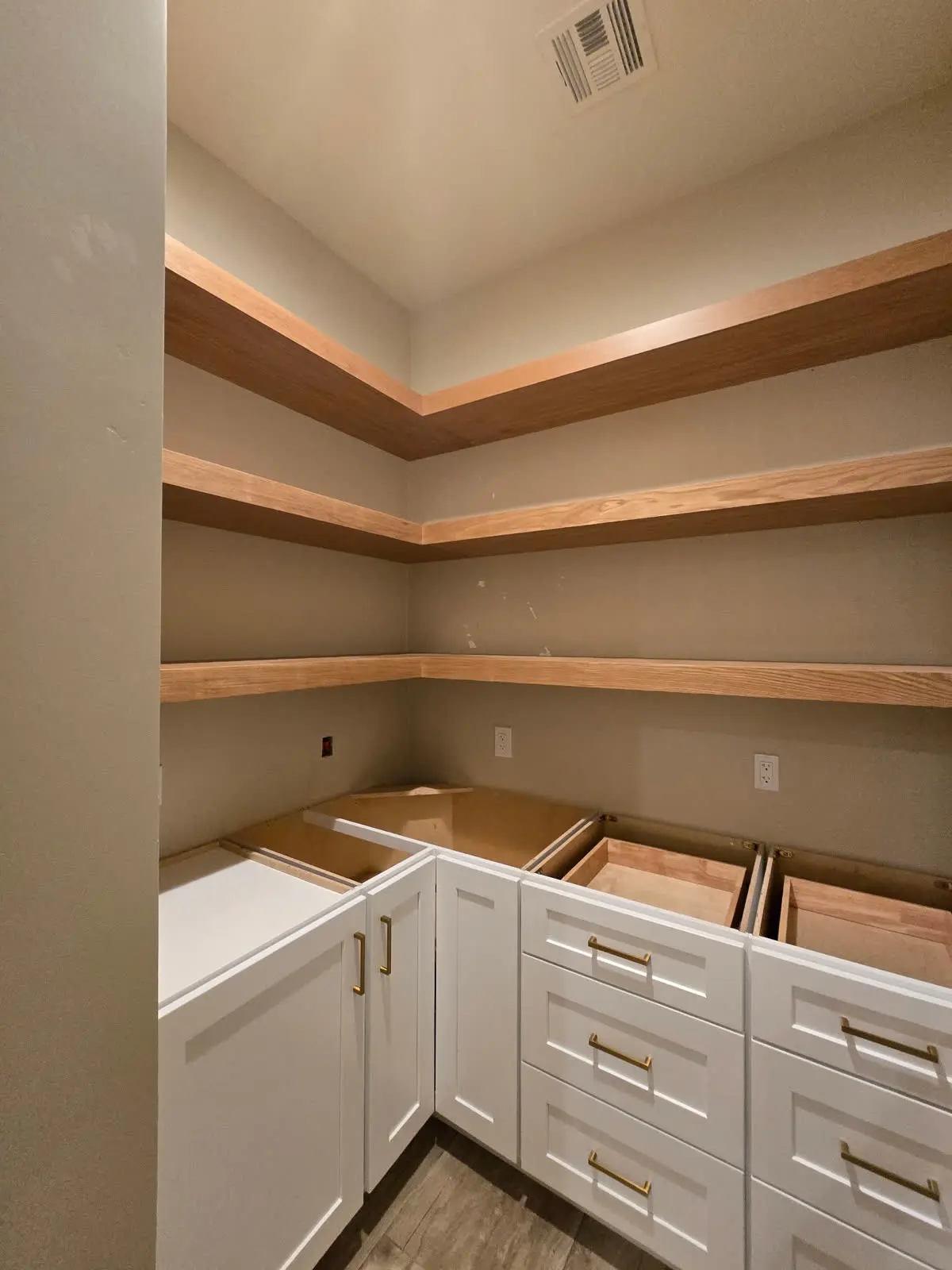Walk-in pantry with white cabinets drawers and wood shelves by DC Cabinets